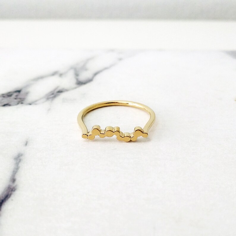 May include: A gold ring with a unique design featuring a series of connected circles.