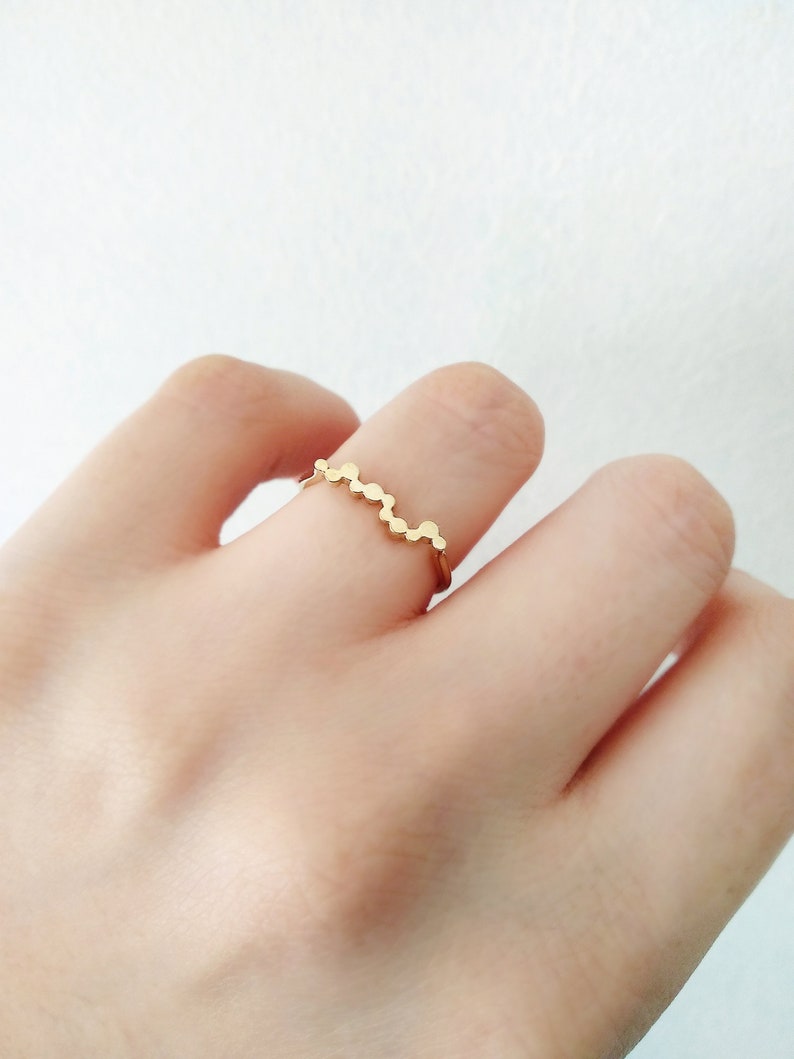 May include: A gold ring with a wavy design made of small, round beads.