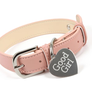 Può includere: Un collare per cani in pelle rosa con una fibbia argentata e un'etichetta a forma di cuore che dice "Good Girl".
