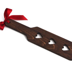 Heart cutout wooden spanking paddle. Available in three different wood stains. Spanking paddles for BDSM play.