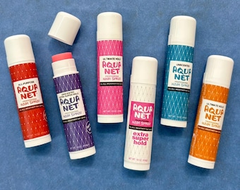 May include: Six different Aqua Net hairspray products in stick form. The products are labeled with different hold strengths, including "All Purpose", "Extra Super Hold", "Ultimate Hold", and "Extra Super Hold".