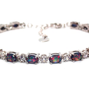 Può includere: Bracciale in argento con pietre di opale nero di taglio ovale e pietre di accento rotonde e trasparenti. Il bracciale ha un design a catena delicato con una chiusura sicura. Gli opali mostrano un vivace gioco di colori.