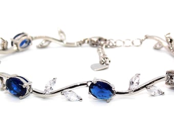 Peut inclure: Un bracelet en argent avec un délicat motif de vigne orné de pierres ovales bleues et blanches.