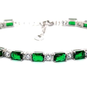 May include: A silver bracelet with emerald green and clear rectangular stones.