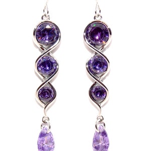 May include: A pair of silver dangle earrings with three round purple gemstones and a teardrop-shaped purple gemstone hanging from the bottom.