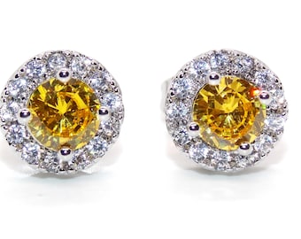 May include: A pair of silver earrings with a round yellow gemstone surrounded by a halo of smaller white gemstones.