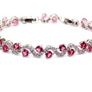 Pode incluir: Uma pulseira prateada com pedras rosas em forma de coração e pedras claras redondas alternadas. A pulseira tem um design delicado e elegante, perfeito para adicionar um toque de brilho a qualquer roupa.