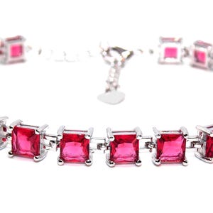 May include: A silver bracelet featuring a row of square-shaped pink gemstones. The bracelet has a lobster clasp fastening.