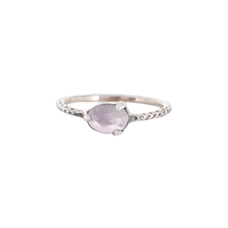 May include: A silver ring with a textured band and a light purple gemstone.