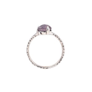 May include: A silver ring with a textured band and a purple gemstone.