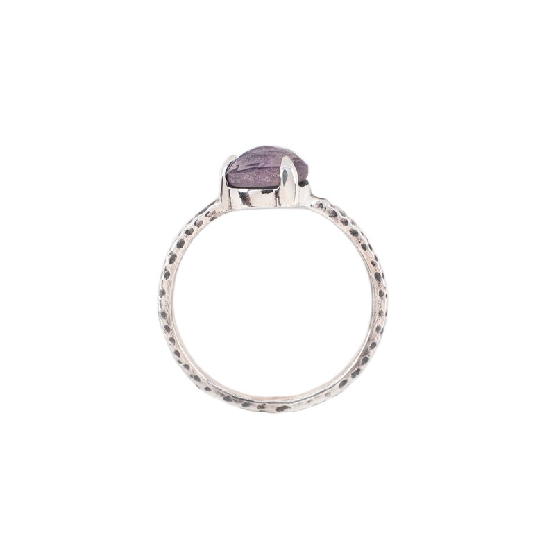 May include: A silver ring with a textured band and a purple gemstone.