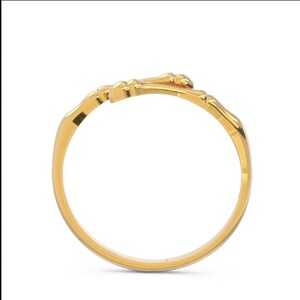 K&ouml;nnte beinhalten: Ein goldener Ring mit einem einzigartigen Design, das zwei ineinander verschlungene knochenartige Formen zeigt.