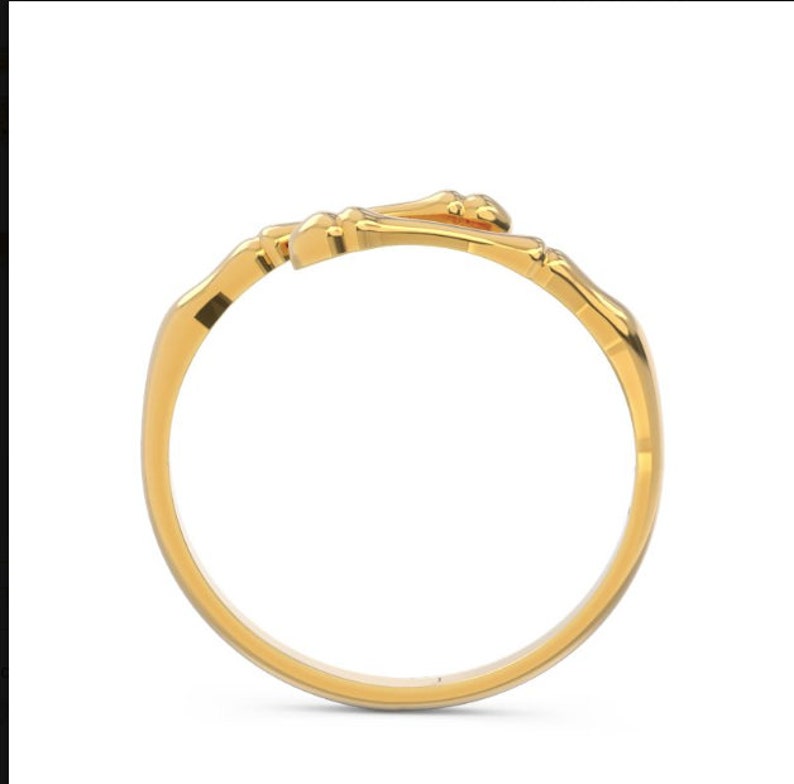 K&ouml;nnte beinhalten: Ein goldener Ring mit einem einzigartigen Design, das zwei ineinander verschlungene knochenartige Formen zeigt.
