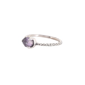 May include: A silver ring with a textured band and a purple gemstone.