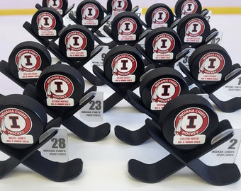 May include: A collection of black and white hockey trophies with the words "Indiana Chiefs" and "Hockey" on them. The trophies are on black stands with a white number on each stand.