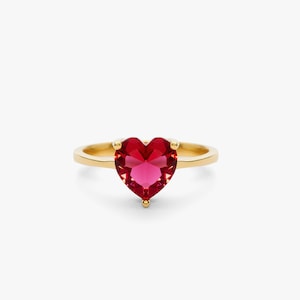 May include: A gold ring with a red heart-shaped gemstone.