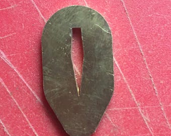 May include: A brass sword guard, also known as a tsuba, with a narrow, vertical opening in the center. The tsuba is oval-shaped and has a slightly rounded edge.