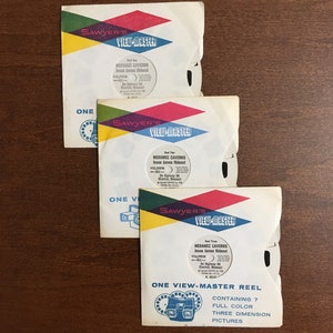 May include: Three vintage View-Master reels with colorful labels. Each reel features the text "Sawyer's View-Master" and "Meramec Caverns Jesse James Hideout". The reels are labeled "Reel One", "Reel Two", and "Reel Three". The bottom reel has the text "One View-Master Reel Containing 7 Full Color Three Dimension Pictures".