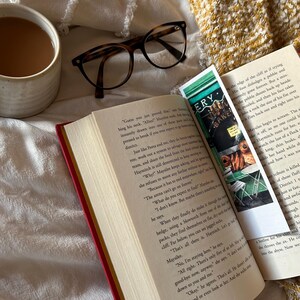 May include: A cozy scene featuring a cup of coffee, eyeglasses, and an open book with a bookmark. The book has red edges and the bookmark has the word "ERY" on it. The eyeglasses have a tortoise shell pattern. The scene is set on a textured white and yellow surface.