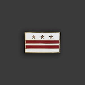 May include: Rectangular pin featuring the flag of Washington, D.C. The pin has a white background with two horizontal red stripes and three red stars. The pin is framed with a gold border.