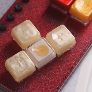 May include: A close-up of a red keyboard with gold and white keycaps. The keycaps have a pearlescent finish and the gold keycap has the word "DROP" printed on it.