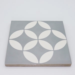 May include: A gray ceramic tile with a white geometric pattern of overlapping circles. The tile has a slightly textured surface.
