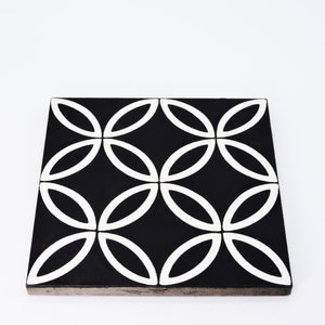 May include: Black and white ceramic tile with a geometric pattern of overlapping circles. The tile has a matte finish and is suitable for use in kitchens, bathrooms, and other areas.