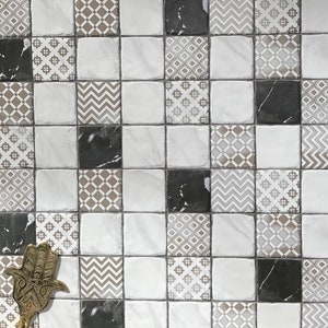 May include: A white tiled wall with a geometric pattern. The tiles are arranged in a checkerboard pattern with black and white marble tiles interspersed. The tiles have a variety of patterns, including diamonds, zigzags, and floral designs.