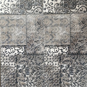 May include: A decorative tile pattern featuring a patchwork design with floral and scrollwork motifs. The color palette includes shades of gray, black, and white, creating a vintage aesthetic. The tiles have a textured appearance.