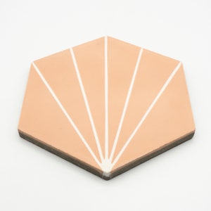 May include: A peach-colored hexagonal tile with a white sunburst design. The tile has a slightly textured surface.