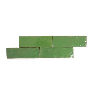 May include: A collection of five rectangular, glossy, green tiles arranged in a staggered pattern. The tiles have a slightly uneven surface and a rustic appearance, suggesting a handmade or vintage aesthetic. The background is plain white.