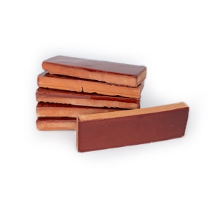 May include: A stack of six rectangular terracotta tiles in a deep reddish-brown color. The tiles are slightly uneven and have a rustic appearance.
