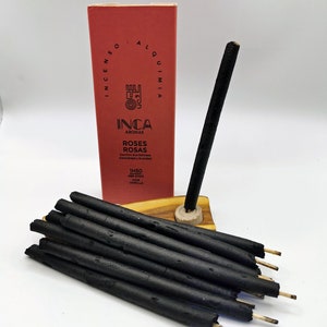 Puede incluir: Una caja de inciensos negros con una etiqueta roja que dice "INCA AROMAS ROSES ROSAS Comfort and Freshness Comodidad y Frescura 1H50 PER STICK POR VARILLA".