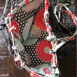 May include: A black and white fabric tote bag with a floral lining. The lining features red, blue, and white flowers on a black background with white polka dots.