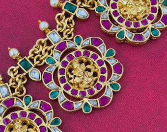 May include: Gold necklace with multiple round pendants featuring a deity figure in the center, surrounded by pink, green, and white stones.