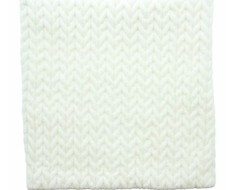 May include: White knitted throw blanket with a cable knit pattern.