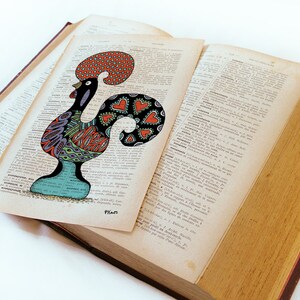 Peut inclure: Une illustration color&eacute;e d'un coq avec un motif rouge, orange, bleu, vert et violet sur une page d'un vieux livre. Le coq est un symbole traditionnel du Portugal.
