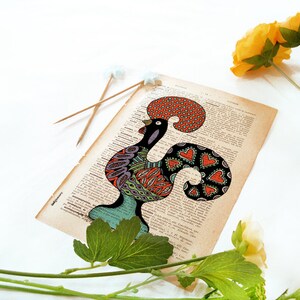 Peut inclure: Une illustration color&eacute;e de coq dessin&eacute;e sur une page de livre vintage. Le coq est noir, vert, rouge, orange et violet. Le coq est entour&eacute; de fleurs blanches et de feuilles vertes.