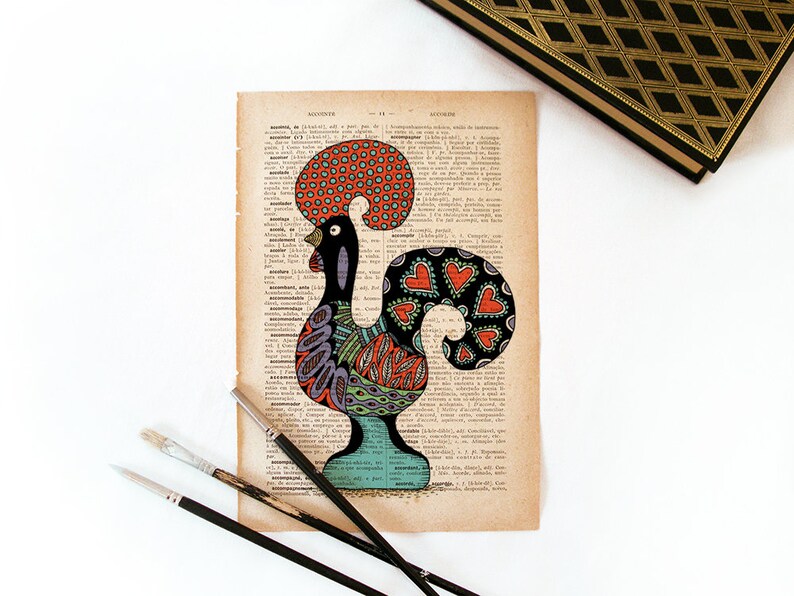 Peut inclure: Une illustration color&eacute;e de coq avec un corps noir, une cr&ecirc;te rouge et orange et une queue avec des c&oelig;urs rouges, dessin&eacute;e sur une page de livre vintage.