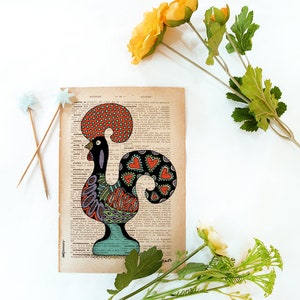 Peut inclure: Une illustration color&eacute;e d'un coq, symbole national du Portugal, sur une page de livre vintage. Le coq est dessin&eacute; dans un style d'art populaire avec des couleurs rouge, orange, vert, bleu et noir. Le coq est entour&eacute; de texte sur la page.