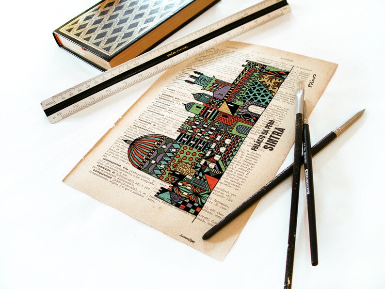 May include: A colorful illustration of the Palacio da Pena in Sintra, Portugal, printed on a vintage book page. The illustration is surrounded by text and is accompanied by three paintbrushes.