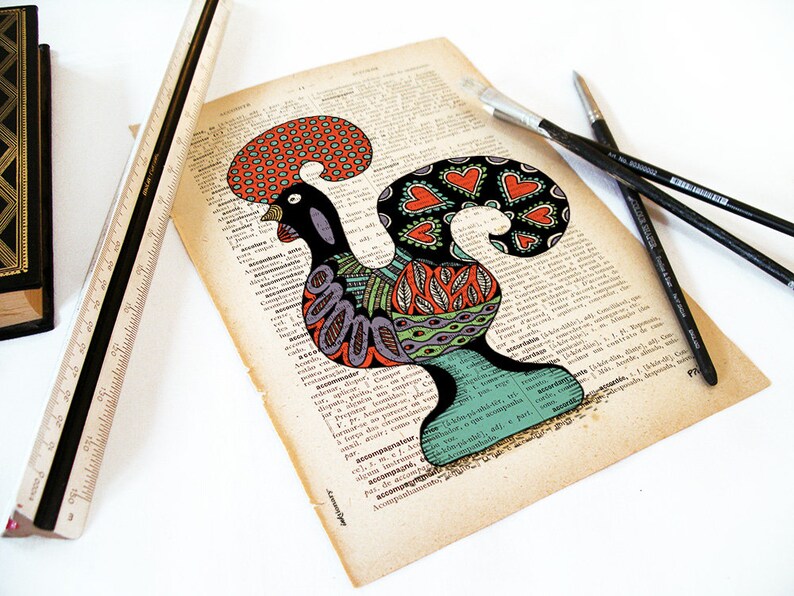Peut inclure: Une illustration color&eacute;e de coq sur une page de dictionnaire vintage. Le coq est dessin&eacute; dans un style d'art populaire avec des couleurs noires, rouges, orange, vertes et bleues. Le coq se tient sur une base verte.