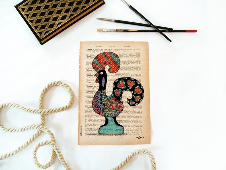 Peut inclure: Une illustration color&eacute;e de coq sur une page de dictionnaire vintage. Le coq est dessin&eacute; en noir, rouge, orange, vert, bleu et violet. La cr&ecirc;te du coq est rouge et orange, et ses plumes de queue sont noires avec des c&oelig;urs rouges. Le coq se tient sur une base bleue et verte.