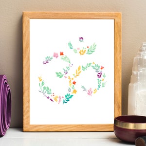 May include: A framed print of a floral Om symbol in shades of green, yellow, pink, and purple. The Om symbol is a spiritual symbol in Hinduism and Buddhism.