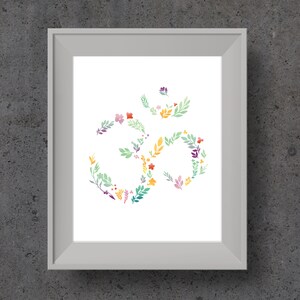 May include: A white framed print with a floral design of the Om symbol in shades of green, yellow, orange, pink, and purple.