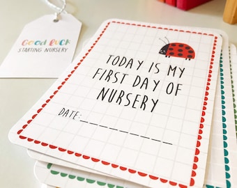 May include: A stack of white cards with red, green, and blue borders. Each card has a ladybug illustration and the text "TODAY IS MY FIRST DAY OF NURSERY" with a line for the date.
