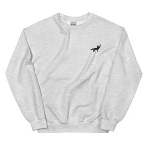 Puede incluir: Una sudadera gris jaspeada con un pequeño gráfico de zorro negro en la parte delantera.