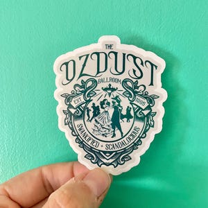 May include: A white sticker with a teal green design. The sticker features the text "The OzDust Ballroom Est 1995 Swankified + Scandalous". The design includes a couple dancing and a chandelier.