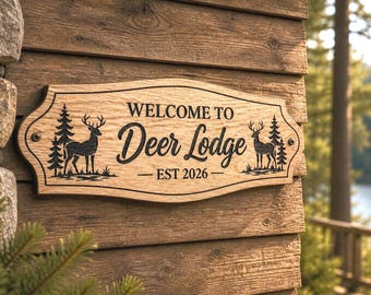 Op de afbeelding: Houten bord met de tekst "WELCOME TO Deer Lodge EST 2026". Het bord heeft een decoratieve rand en toont silhouetten van herten en dennenbomen. Het bord is op een houten muur gemonteerd.