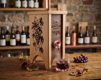 May include: A wooden beverage dispenser with a light oak frame and a dark wood front panel featuring a laser-engraved grape vine design and the text THE DIMITROV FAMILY. It includes a white and red plastic spigot and a glass of red wine.